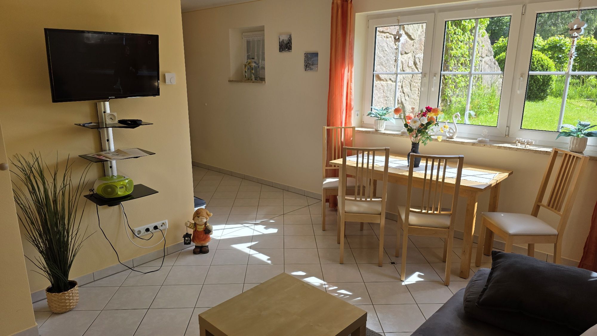 Wohnbereich mit Sofa, Fernseher, Tisch und Stühlen